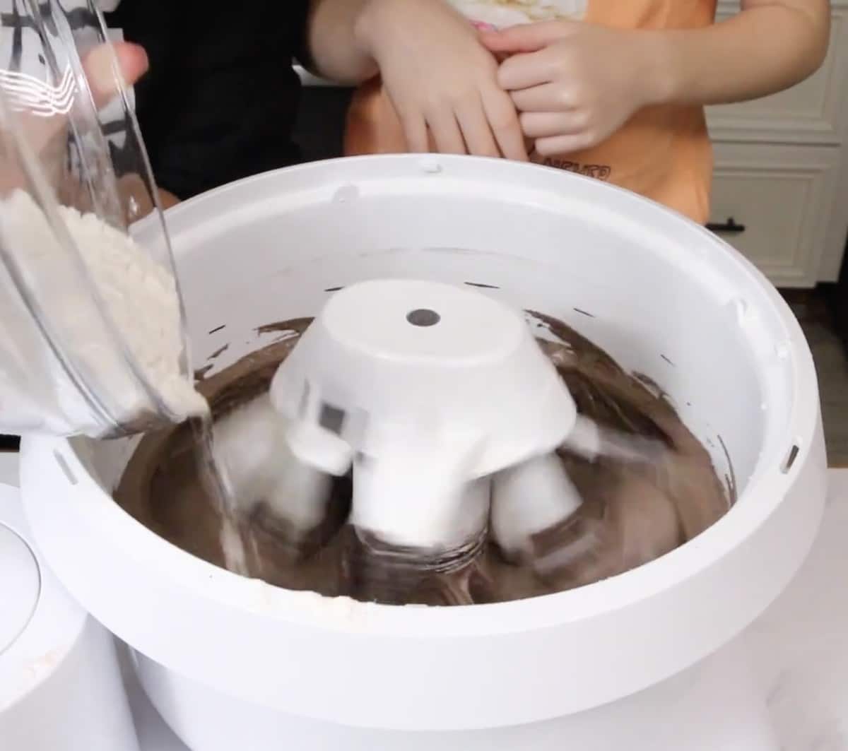 Adding flour to black velvet cake batter in a stand mixer.