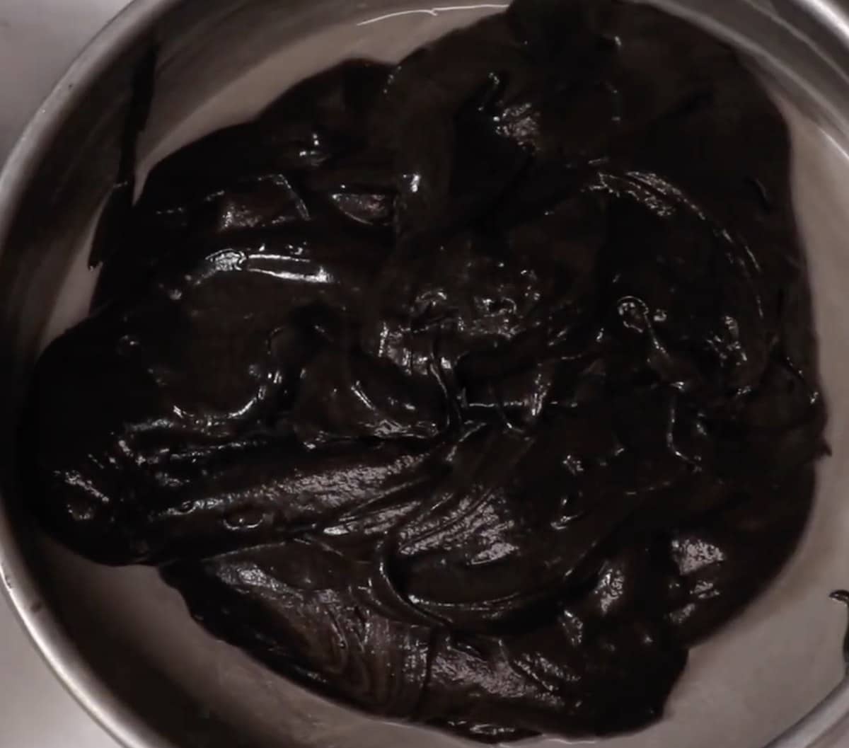 Black velvet cake batter spread in a cake pan.