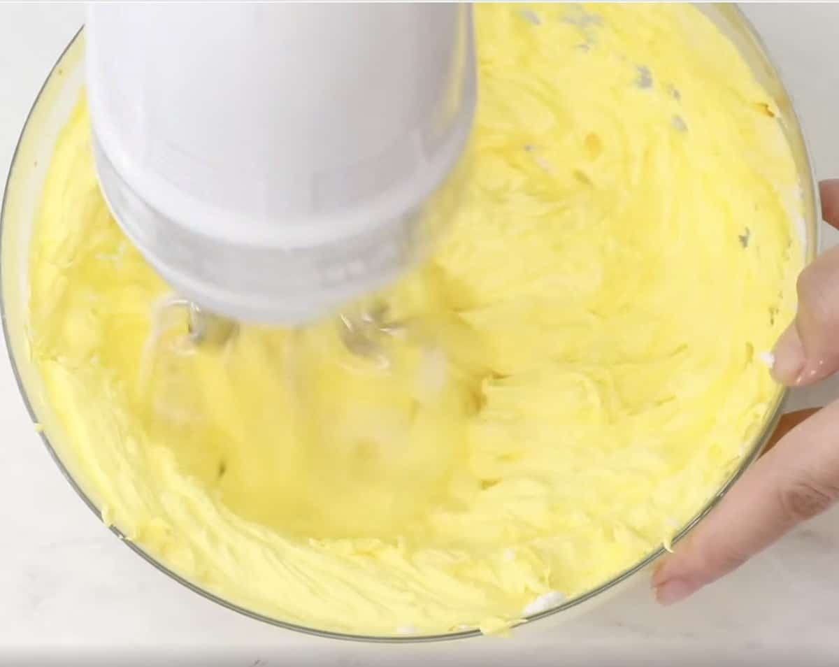 Yellow buttercream being mixed in a bowl.