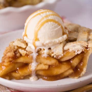 Slice of caramel apple pie with as scoop of ice cream and drizzled caramel on top.