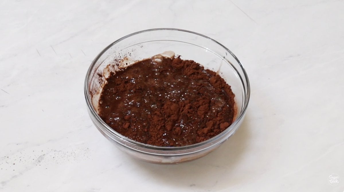 Dutched cocoa powder whisked into boiling water in a glass bowl.