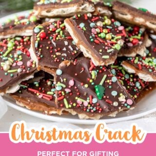 Pile of Christmas crack pieces with chocolate and holiday sprinkles on a white plate.