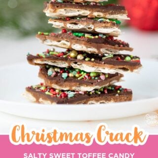 Tall stack of Christmas crack pieces topped with red and green sprinkles on a white plate.