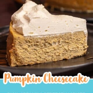Close up of a slice of pumpkin cheesecake topped with whipped cream on a black plate