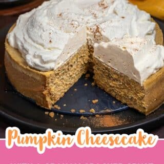 Whole pumpkin cheesecake topped with whipped cream and pumpkin spice with one slice cut and pulled forward