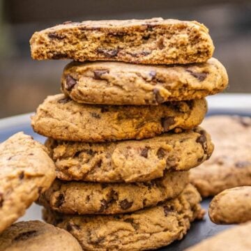 Stack of pumpkin chocolate chip cookies with the top cookie broken in half.