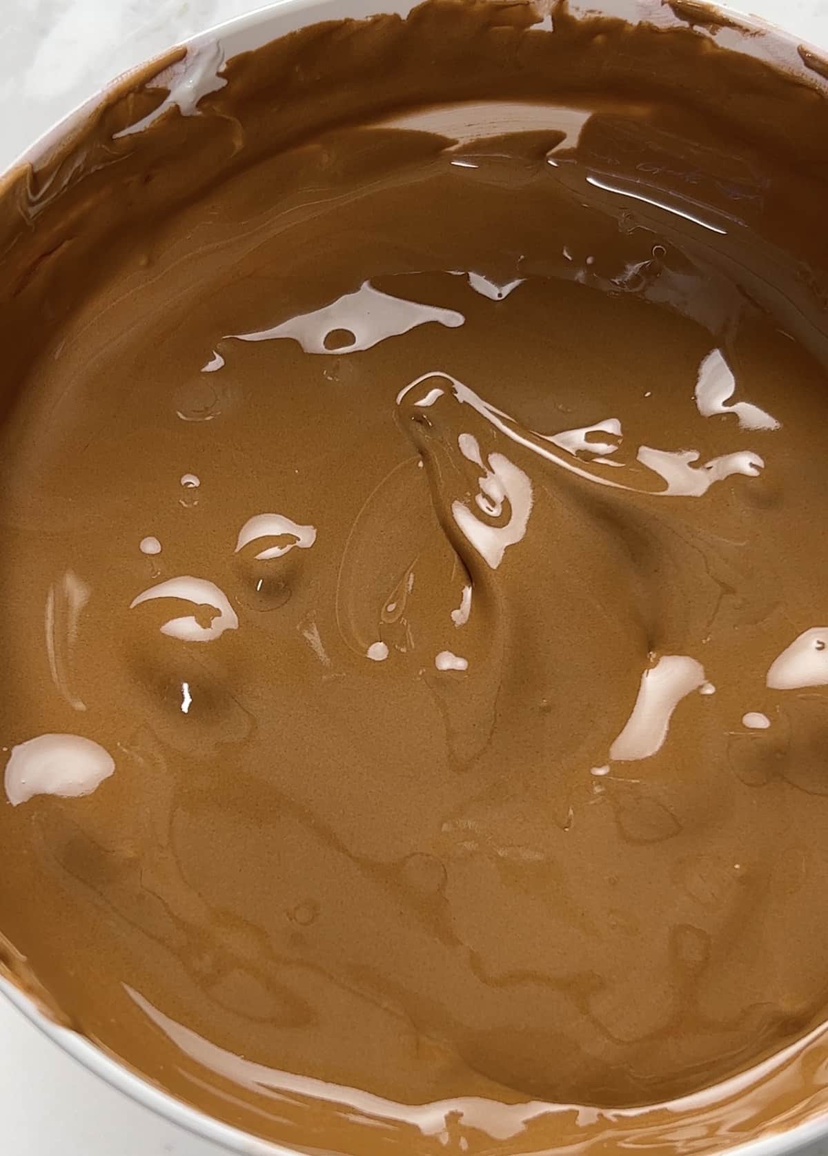 Thinned brown royal icing flowing off a spatula.
