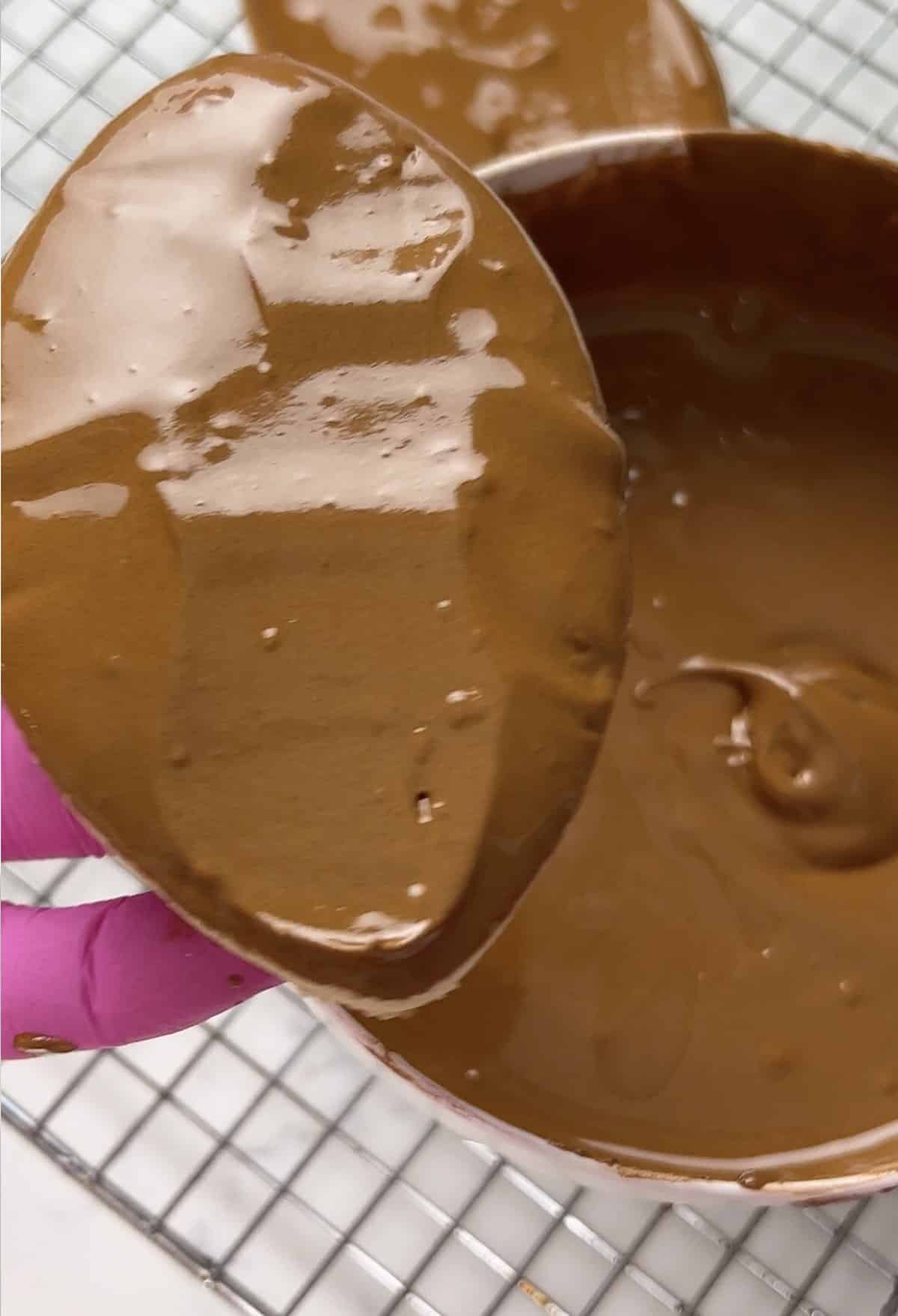 Dipping a football cookie into brown royal icing.