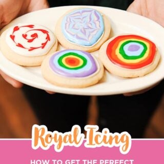 Plate of sugar cookies decorated with royal icing in rainbow, swirl, and marbled designs.