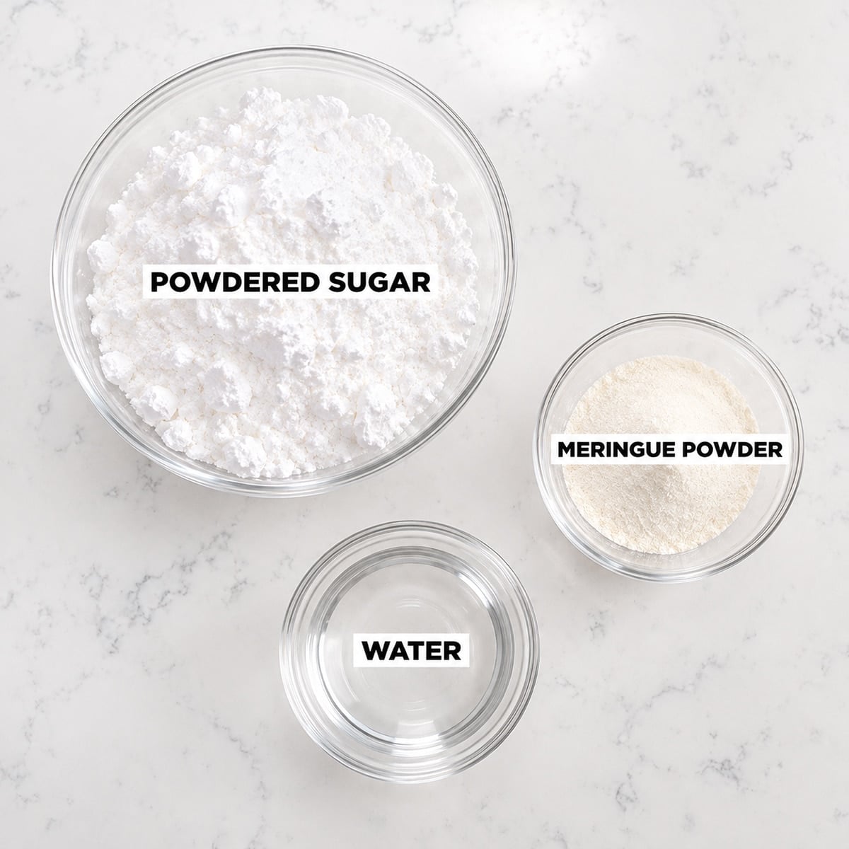 Royal icing ingredients in glass bowls: powdered sugar, meringue powder, and water.